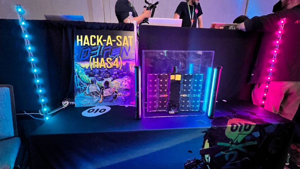 The Hack-a-Sat logo with a replica of the satellite teams hacked into at DEF CON 31.
